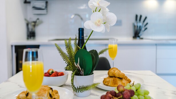 Desayuno con croissants, uvas, fresas y un vaso de jugo de naranja sobre una mesa de mármol.