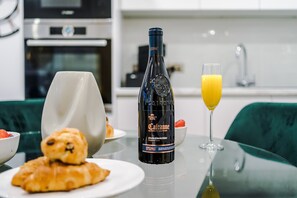 A breakfast setting with a bottle of Cava, a glass of orange juice, croissants, and a bowl of strawberries. - Skeek Groundfloor Apartment with Wine Fridge (Birmingham)