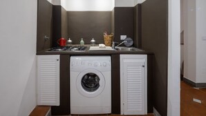 A compact laundry room with a washing machine, a sink, and a small countertop with various items. - San Giuseppe Apartment (Firenze)