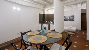 A compact living space with a dining table, chairs, a sofa, a kitchen area, and a bed. - San Giuseppe Apartment (Firenze)