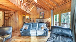 Un interior de madera con un sofá de cuero, una escalera y una chimenea de piedra.