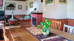 A dining area with a wooden table, chairs, a potted plant, and a brick fireplace. - Cozy apartment in Chwarzenko with WiFi (Chwarzenko)