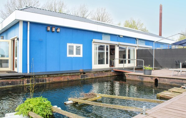A blue building with a dock extending into a body of water, a door, and a window.
