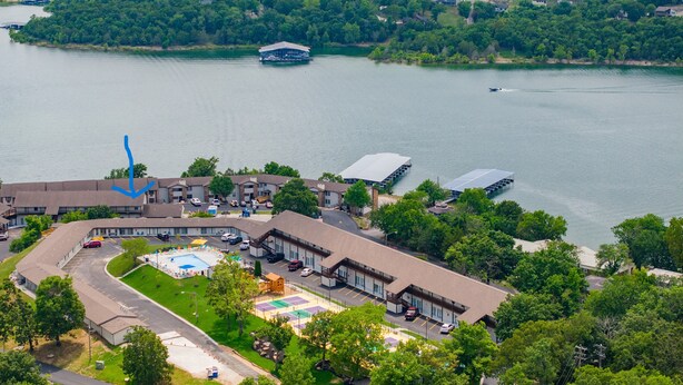 An aerial view of a hotel with a swimming pool, tennis courts, and a boat dock.