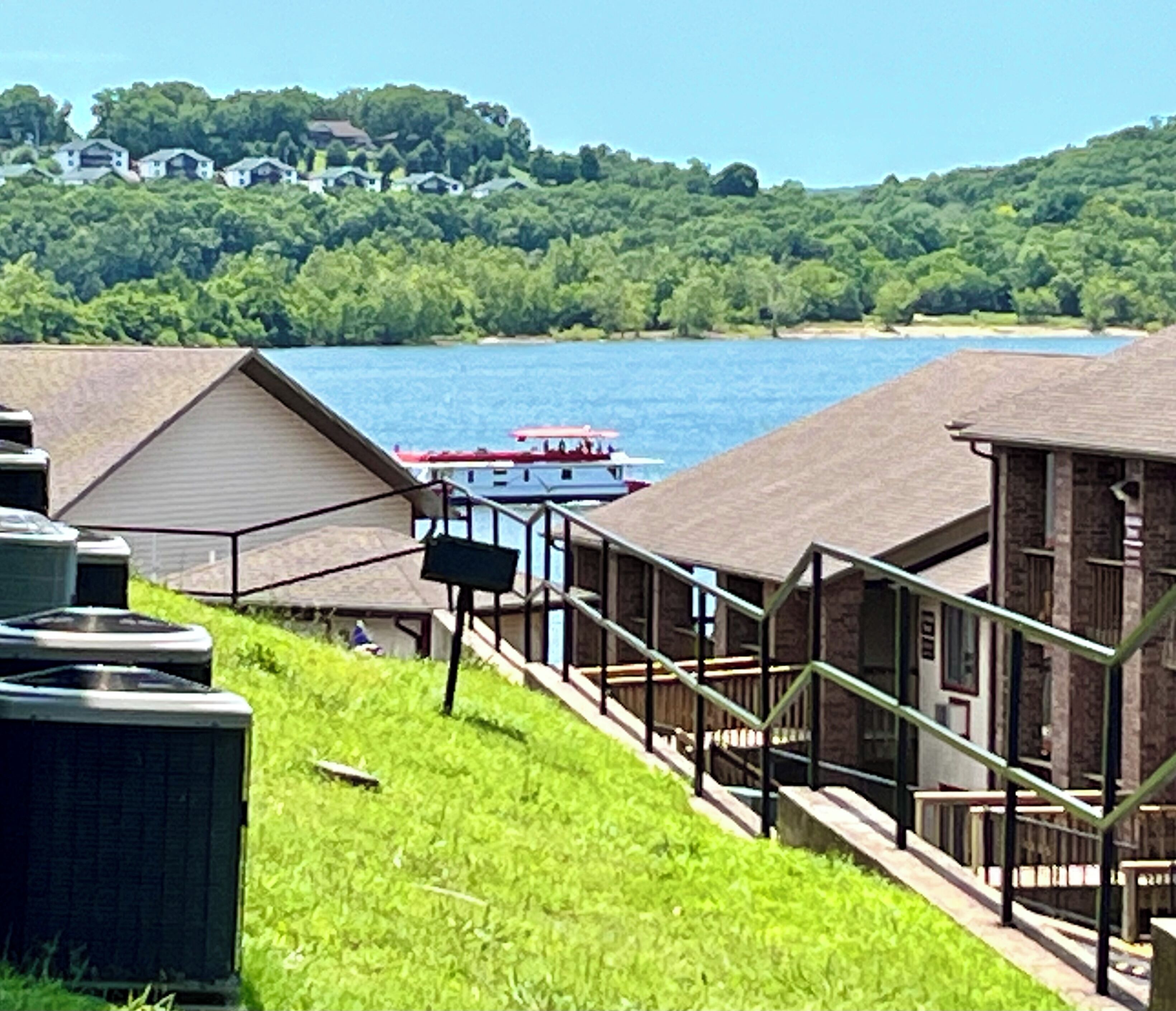 A lakeside property with a dock, a boat, and a view of houses across the water.