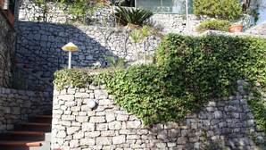 A stone staircase with a lantern, surrounded by greenery and a stone wall.