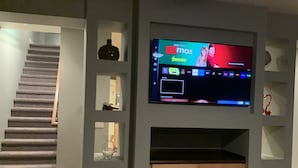 A living room with a flat-screen TV mounted on a wall, a staircase, and built-in shelving. - Modern, king beds, pools, parks, pet OK, 5 mins toYMCA ,Store and top golf (Meridian)