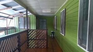 Un couloir doté d’un plancher en bois, de murs verts et d’une rambarde en métal.