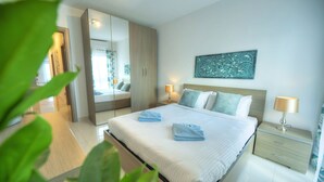 A modern hotel room with a large bed, a nightstand, a mirror, and a wall-mounted artwork. - Modern, large 3bedroom, spectacular views GOSLM-9 (Sliema)