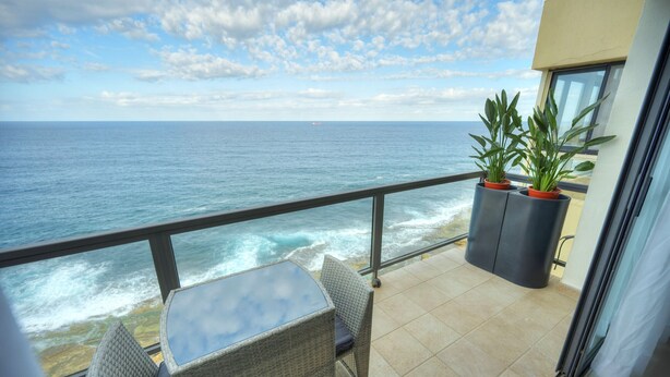 A balcony with a view of the ocean, wicker furniture, and potted plants. - Modern, large 3bedroom, spectacular views GOSLM-9 (Sliema)