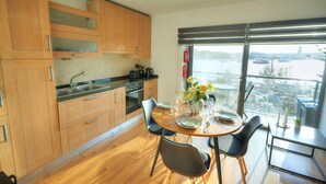 Una cocina moderna con armarios de madera, un comedor con mesa redonda y un ventanal con vistas a un puente y al agua.