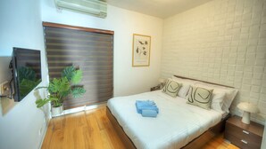 Un dormitorio con cama, mesita de noche, lámpara, equipo de aire acondicionado y una planta en maceta.