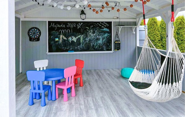 Relax in a cozy room with a chalkboard, colorful chairs, hammock, and a bean bag, perfect for a creative retreat.