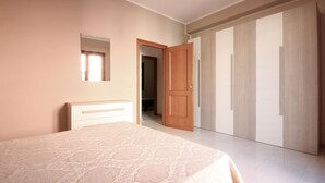 Una camera da letto con un letto, un armadio, uno specchio e una porta che dà su un'altra stanza.