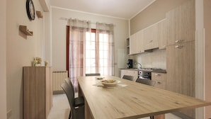 Una cucina moderna con mobili in legno, un tavolo da pranzo con sedie e una finestra con tende.
