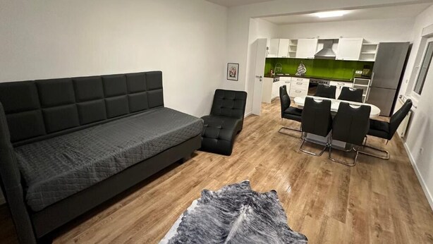 Un salon moderne comprenant un canapé, un petit fauteuil et un coin repas avec une table et des chaises.