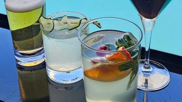 A poolside bar with a variety of drinks, a clear pool, and a view of the cityscape. - ALT Urbana (León)