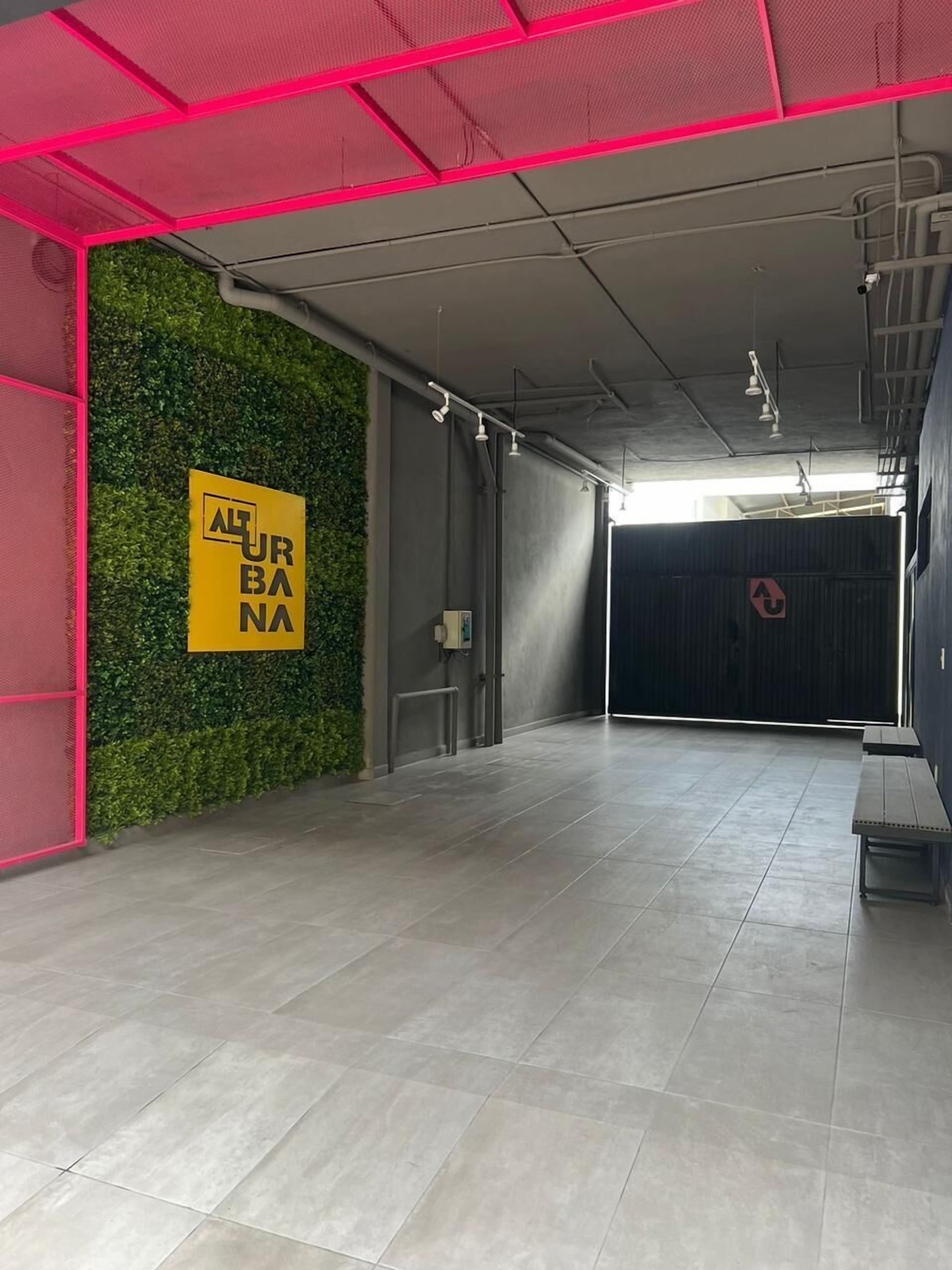 A spacious indoor area with a green wall, a yellow sign, and a grey floor.