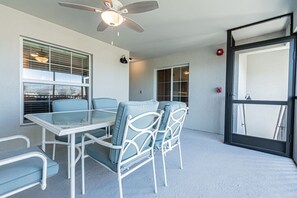 A room with a glass table and chairs, a ceiling fan, and a door with a window.