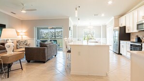 A spacious living area with a large island, a dining table, and a sofa.