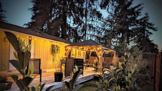 A wooden cabin with a covered patio area, outdoor seating, and string lights.