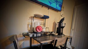 A small kitchen area with a coffee maker, a microwave, and a TV mounted on the wall.