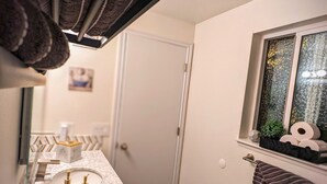 A bathroom with a marble sink, a towel rack with towels, a window with a view, and a door.