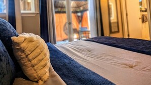 A hotel room with a bed, a large window, and a door leading to a balcony.