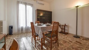 A dining area with a table set for four, surrounded by wooden chairs, a stone-tiled floor, a radiator, and a tall floor lamp. - 1 bedroom cozy apartment in Chiaramonte Gulfi (Chiaramonte Gulfi)