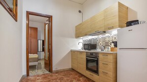 A compact kitchen with wooden cabinets, a built-in oven, a microwave, and a refrigerator. - 1 bedroom cozy apartment in Chiaramonte Gulfi (Chiaramonte Gulfi)