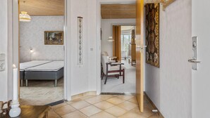 Ein Hotelzimmer mit Bett, Schreibtisch und Stuhl. Am Wand hängt ein Gemälde, die Decke ist aus Holz.