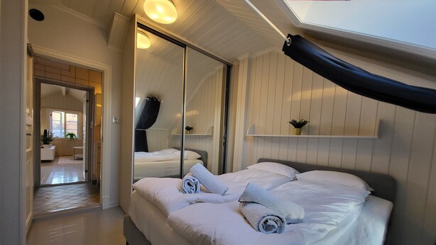 A bedroom with a large bed, a skylight, a mirror, and a view of a bathroom. - Mercury House, Cathedral View! Free parking! (Trøndelag)