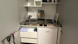 A compact kitchenette with a sink, stove, and storage drawers. - Studio Apartment für 2 - Guestrooms24 - Marl (Marl)
