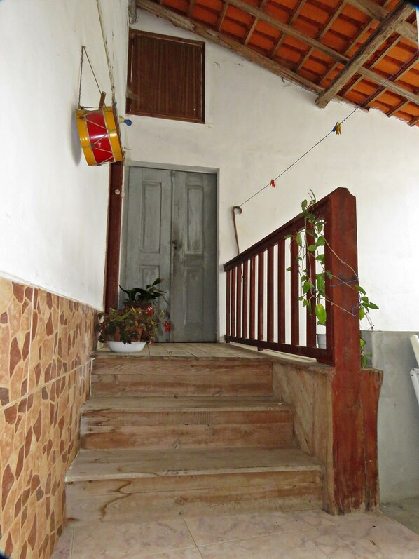 A staircase leading to a door with a wooden railing and a potted plant at the bottom.