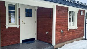 Una casa de madera con puerta y ventana blancas, un pequeño porche y el número 43 en el lateral.