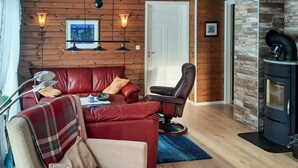 Una sala de estar acogedora con un sofá de cuero rojo, un sillón reclinable y una chimenea.