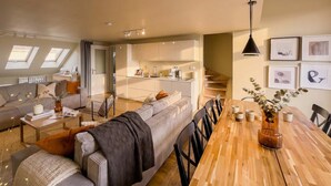 A modern apartment with a living room, dining area, kitchen, and a staircase leading to an upper floor.