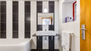 Un baño moderno con bañera, lavabo con espejo y un perchero para toallas.