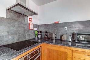 A modern kitchen with a black countertop, stainless steel appliances, and wooden cabinets.