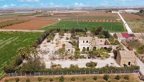 An aerial view of a rural area with fields, a small building complex, and a road.