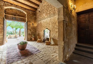 An interior with stone walls, a wooden door, a window, a potted plant, and a patterned rug. - Vacation Home "The Holiday and Art Seahorse House" with Mountain View, Private Pool & Wi-Fi (Vittoria)