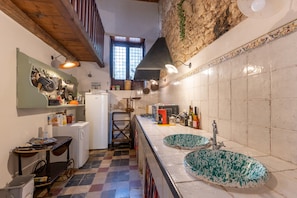 A kitchen with a checkered floor, a sink with a green basin, and a refrigerator.