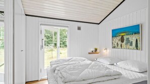 Un dormitorio con cama, puerta corrediza al jardín y un cuadro en la pared.