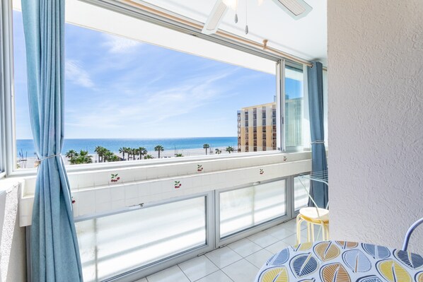 A balcony with a view of the sea and buildings, a chair, and a tiled floor. - Apartment 'Appartement Canet Plage Front Mer' with Sea View, Private Terrace and Air Conditioning (Canet Plage)