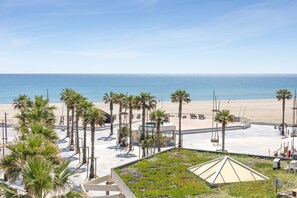 A beachside hotel with palm trees, a sandy beach, and a clear view of the ocean. - Apartment 'Appartement Canet Plage Front Mer' with Sea View, Private Terrace and Air Conditioning (Canet Plage)