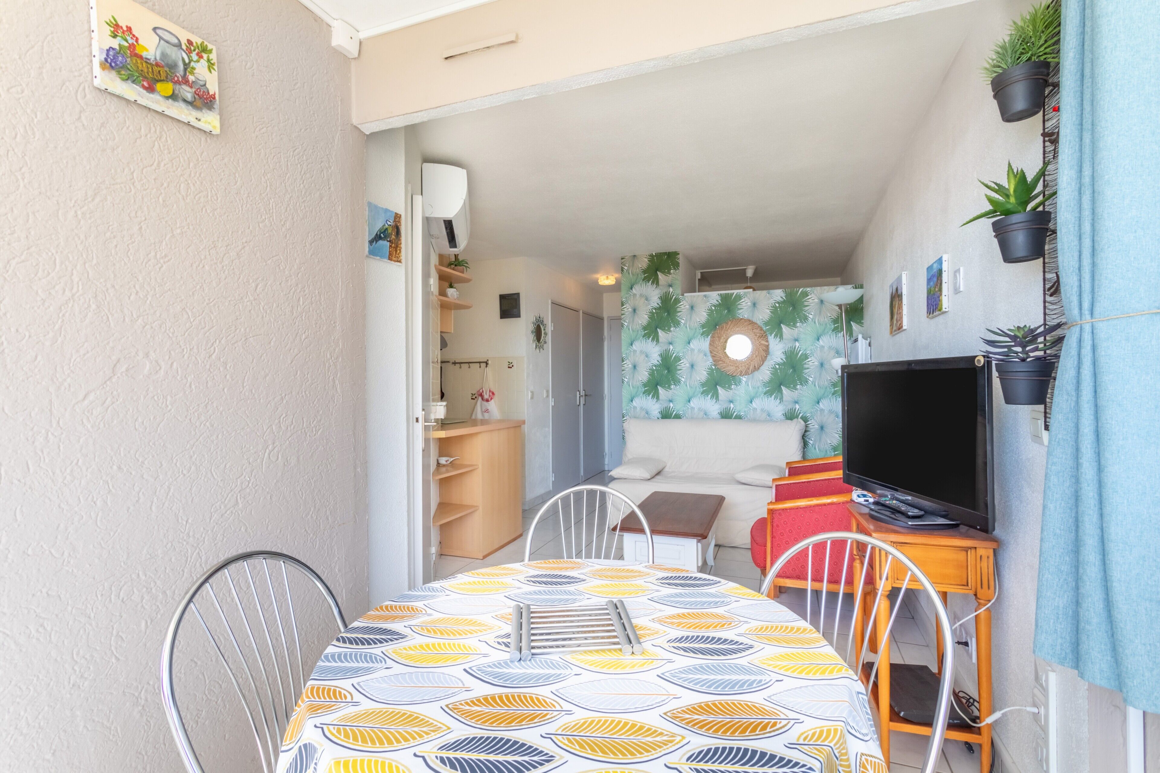 Una habitación con una mesa de comedor, sillas, un televisor y un sofá.
