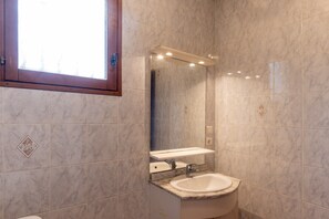 Une salle de bain avec un lavabo, un miroir et une fenêtre.