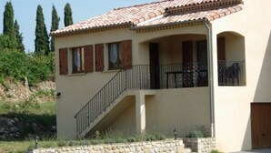 A two-story building with a tiled roof, a stone staircase, and a balcony with a metal railing. - Les Sources Gite Cabernet House with Shared Pool, Private Terrace, and Air Conditioning (Chambonas)