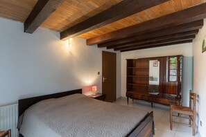 A bedroom with a bed, a wooden wardrobe, a nightstand with a lamp, and a wooden chair. - Charming 'Les Sources Gîte La Grange' House with Shared Pool and Private Terrace (Chambonas)
