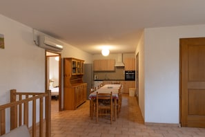 Una cocina con armarios de madera, una mesa de comedor y una escalera.